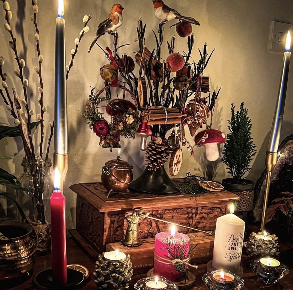 Cozy Winter Solstice living room featuring evergreen garland, candles, natural wood furniture, and warm neutral seasonal decor.