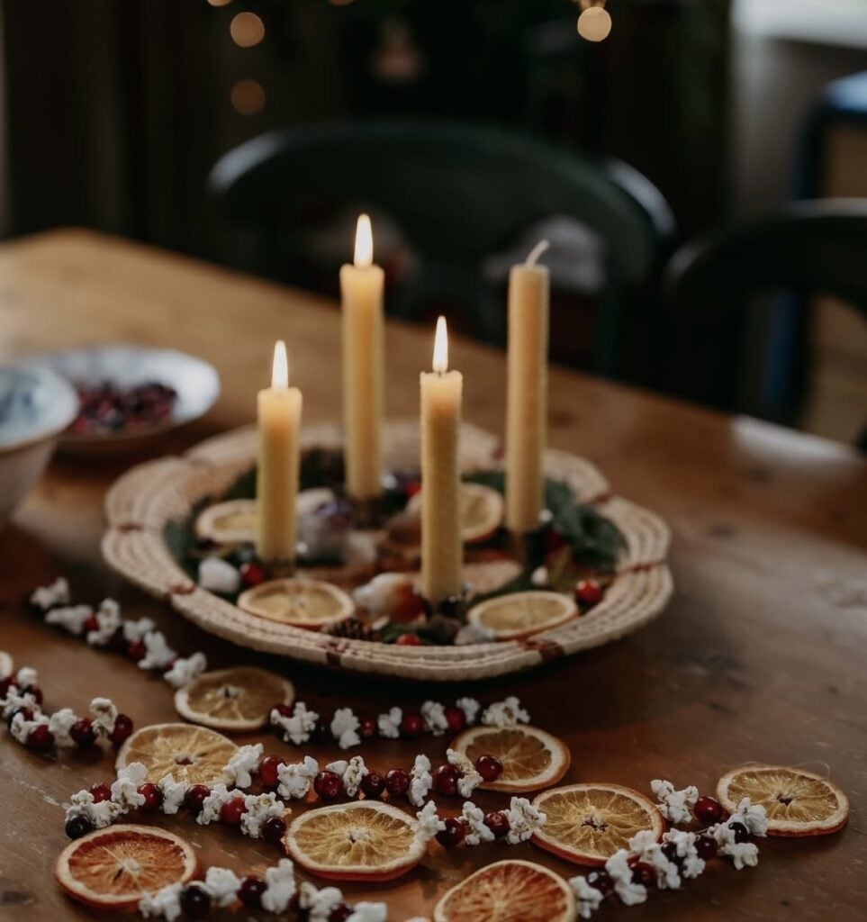 Warm neutral living room featuring evergreen branches, candlelight, rustic wood decor, and natural Winter Solstice decorating inspiration.