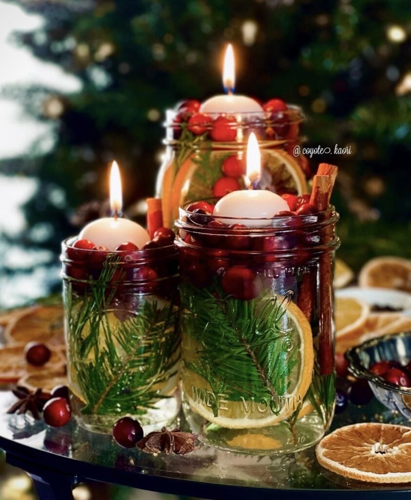 Winter Solstice candle setting with red candles, dried oranges and pine with pine tree in background
