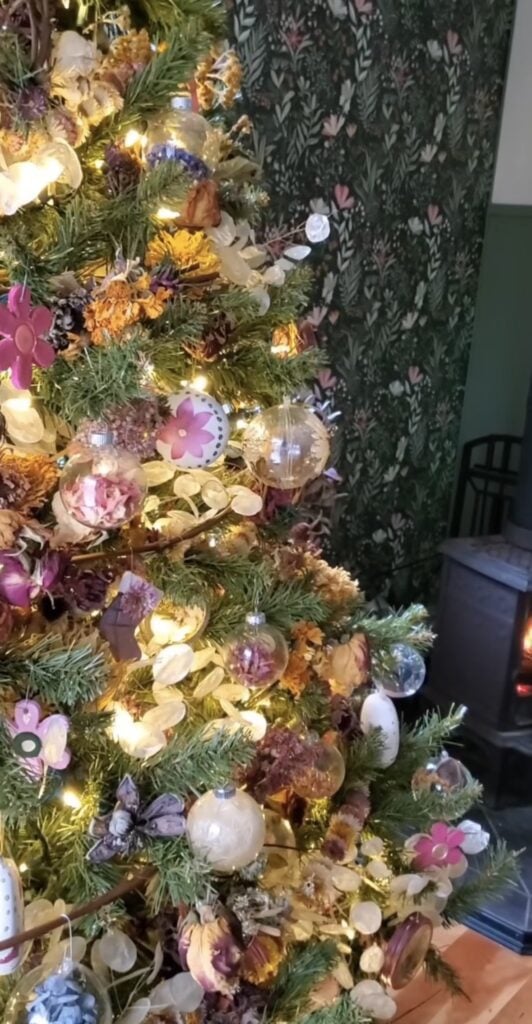 Winter Solstice tree decorated with flowers, evergreen branches, and warm white lights.