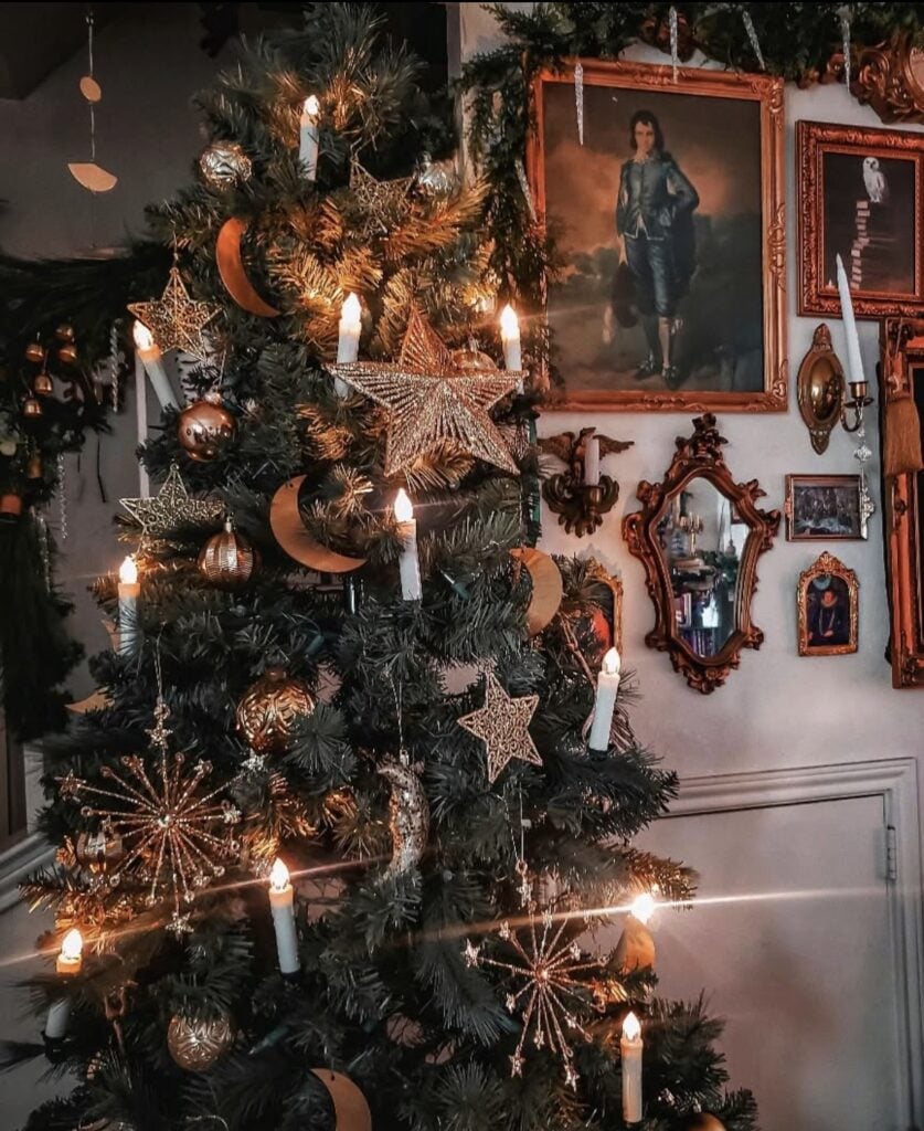 Rustic Winter Solstice tree with evergreen branches, dried oranges, wooden ornaments, pinecones, and warm candlelit woodland decor.