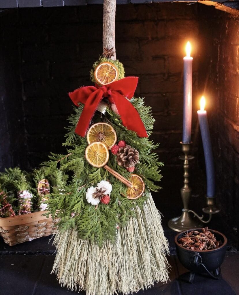 Dried floral and evergreen Winter Solstice broom arrangement featuring candles, natural botanicals, and rustic seasonal styling.