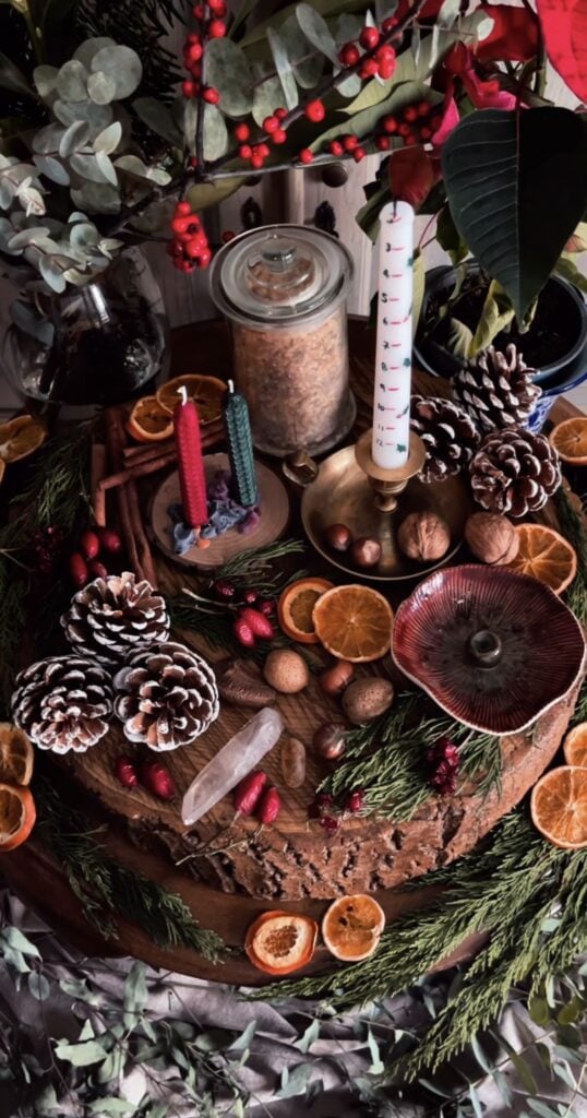 Yule altar decorated with candles, evergreen branches, crystals, dried botanicals, and moon-inspired Winter Solstice decorations.