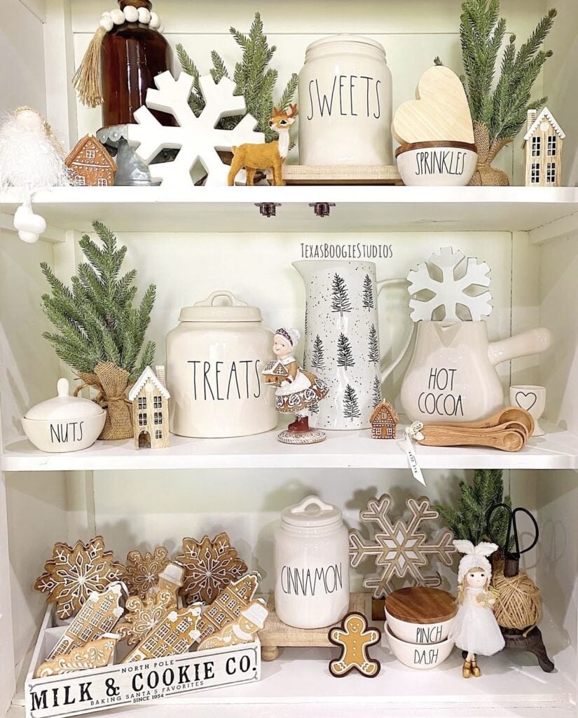 Gingerbread kitchen hutch styled with Rae Dunn canisters, gingerbread houses, cookie village decor, and Christmas greenery, featured by slowestuff.com.