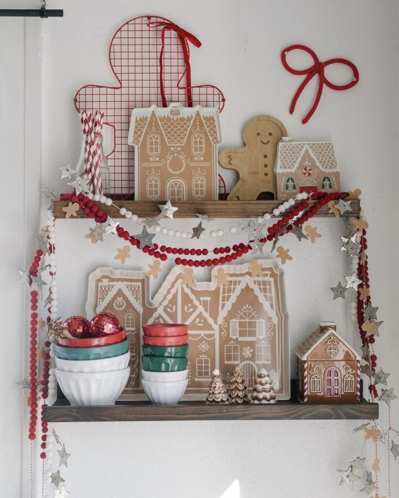 Gingerbread kitchen shelf decorated with red and white garland, gingerbread house plates, and festive Christmas accents, featured by slowestuff.com.