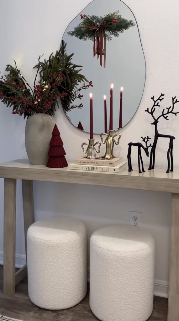Christmas entryway table decorated with red candles, brass reindeer, greenery, and warm neutral holiday accents, featured by slowestuff.com.