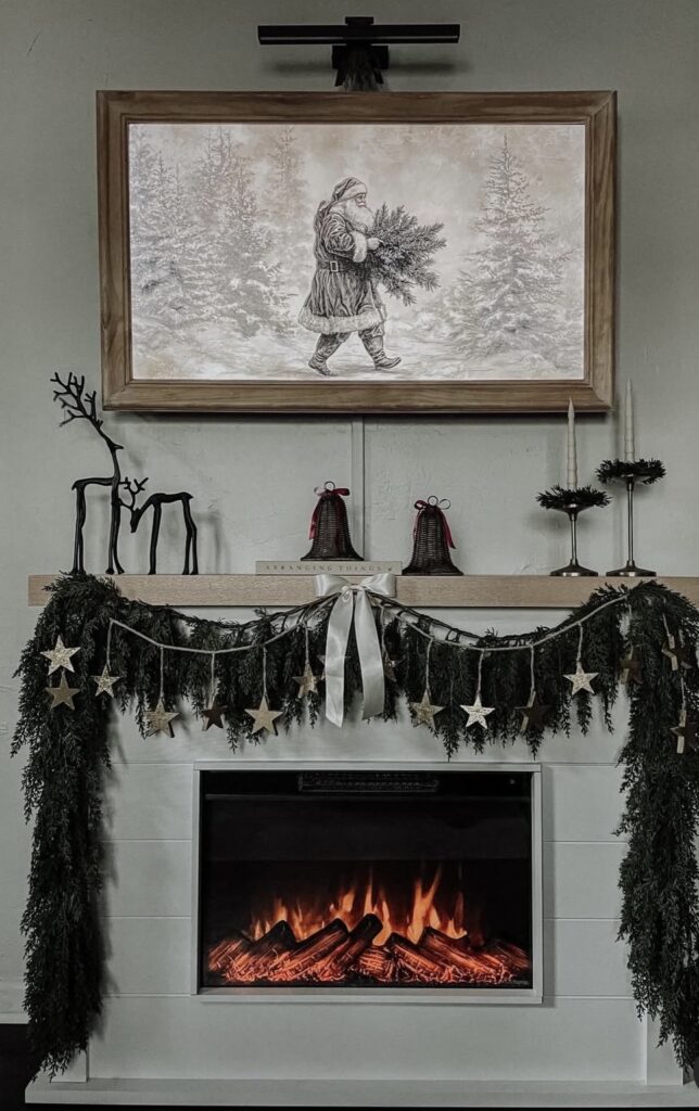 Christmas fireplace mantel decorated with evergreen garland, a star garland, Santa artwork, and festive holiday accents, featured by slowestuff.com.
