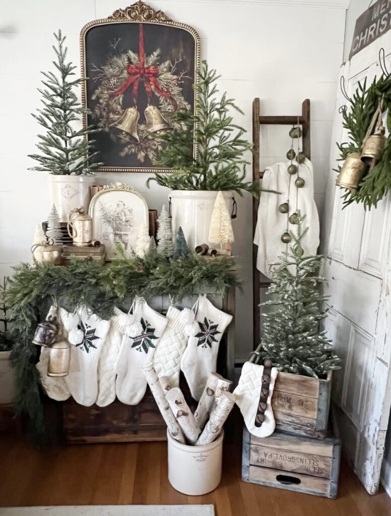 Christmas fireplace mantel styled with white stockings, evergreen garland, and vintage bells for a simple farmhouse holiday look, featured by slowestuff.com.