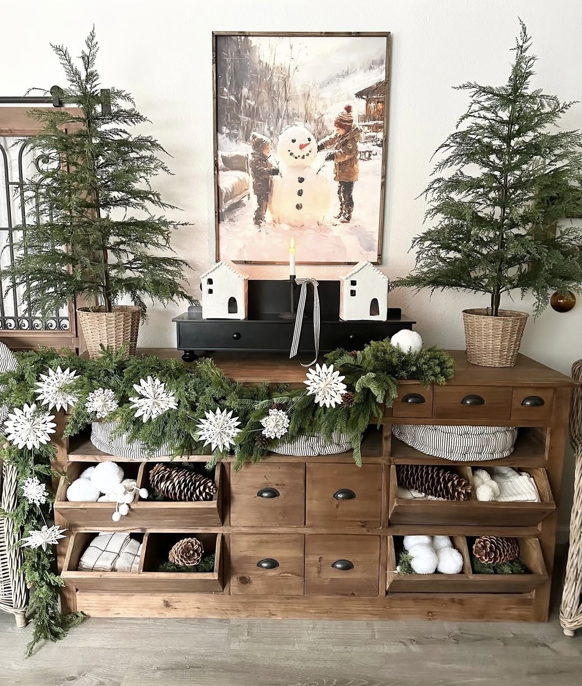 Christmas side table styled with neutral holiday decor and simple seasonal accents with snowflake garland, painting and mini trees for a cozy Christmas home, featured by slowestuff.com.