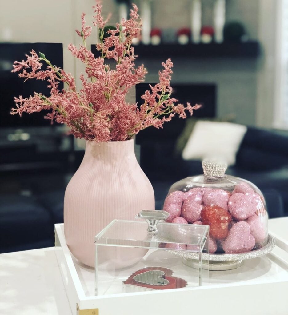 Minimal Valentine tiered tray with neutral decor, a small heart sign, flowers, and greenery.