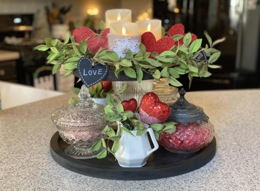 Red Valentine tiered tray styled with roses, heart signs, greenery, and cute candy touches.
