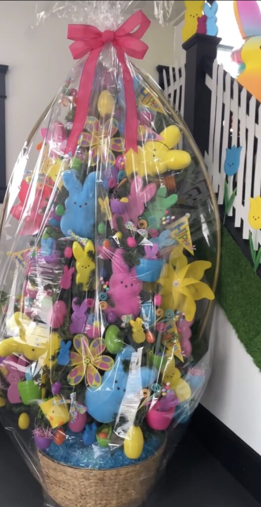 Easter tree wrapped in clear cellophane with a bright pink bow, decorated with colorful Peeps bunnies, plastic eggs, and pastel spring ornaments.