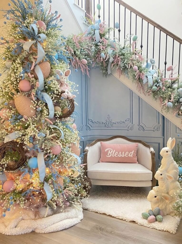 Elegant pastel Easter tree decorated with blue ribbon, pink eggs, and spring florals, styled next to a matching staircase garland and bunny decorations.