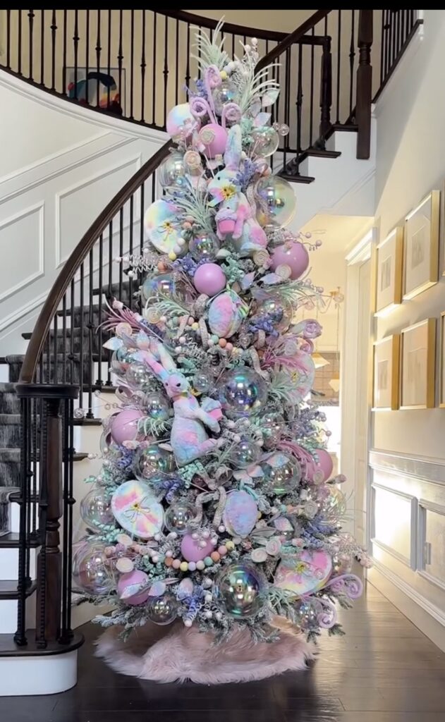 Pastel Easter tree with iridescent ornaments, large eggs, and soft pink and blue spring decor in a bright entryway.