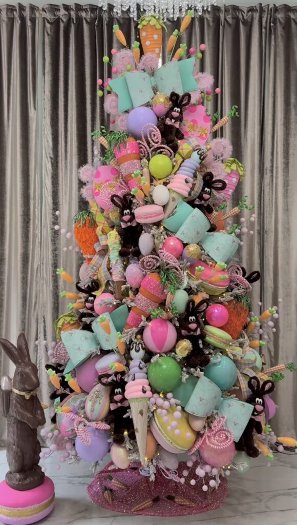 Candy themed Easter tree decorated with giant pastel carrots, bunny plush ornaments, macarons, and bright Easter egg decorations.