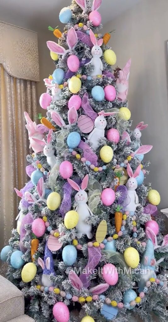 Flocked Easter tree decorated with pastel eggs, bunny ornaments, and purple ribbon garland for a whimsical spring tree look.