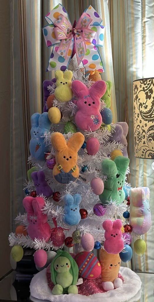 Close up of a bright Easter tree decorated with Peeps bunnies, oversized pastel eggs, shiny ornaments, and candy themed spring decor.