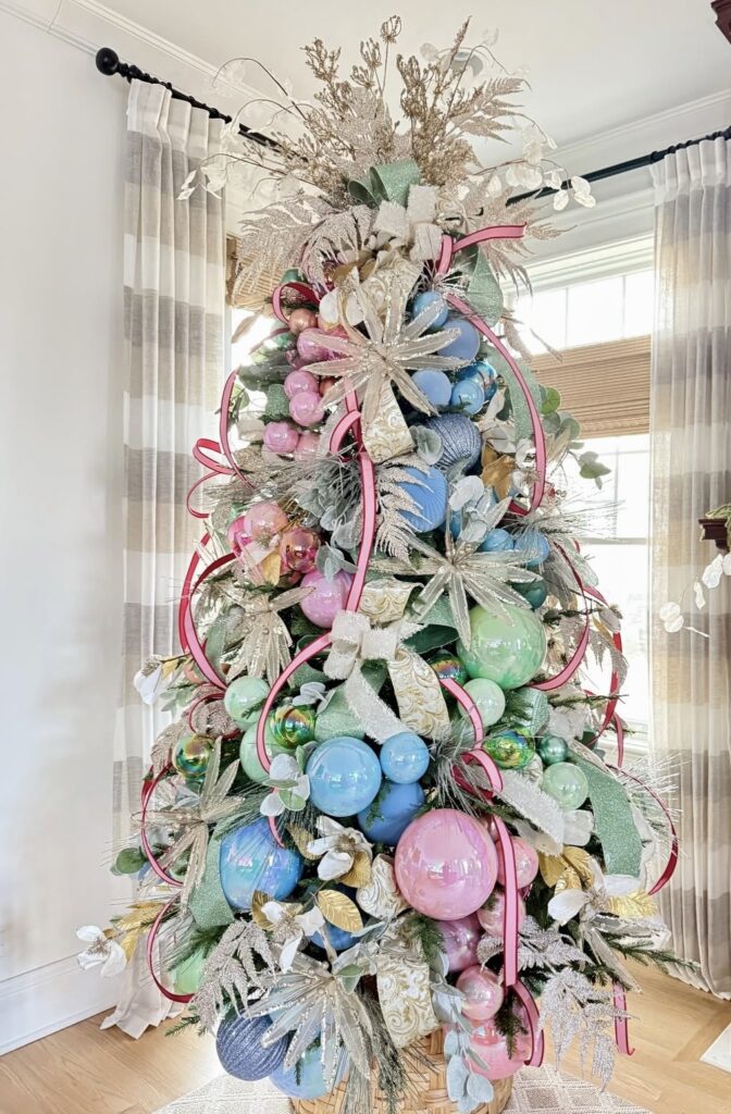 Easter Christmas tree decorated with oversized pastel egg ornaments, pink ribbon garland, silver floral sprays, and spring greenery.