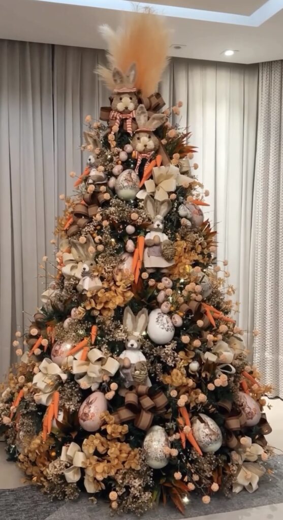 Neutral Easter tree decorated with beige bows, carrots, speckled eggs, and rustic bunny ornaments in warm spring colors.