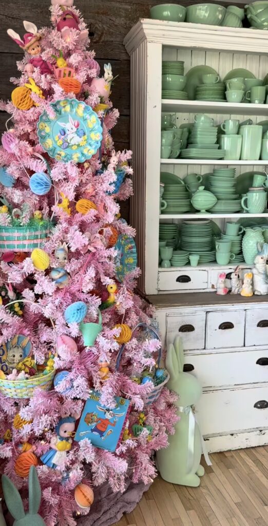 Pink tinsel Easter tree decorated with vintage-style bunny plates, colorful honeycomb eggs, Easter baskets, and playful spring ornaments.