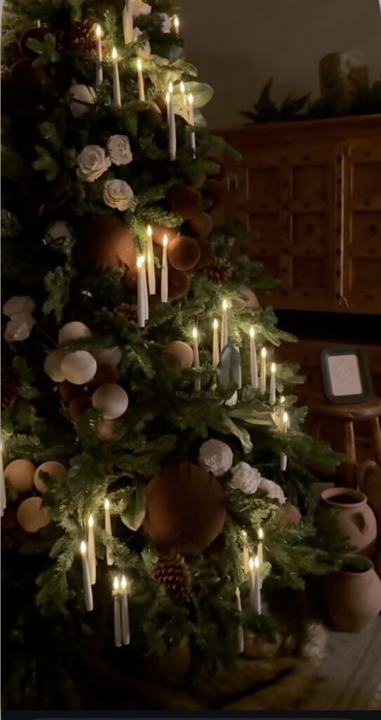 Deep brown Christmas tree decorated with candles, roses, and romantic dramatic holiday details