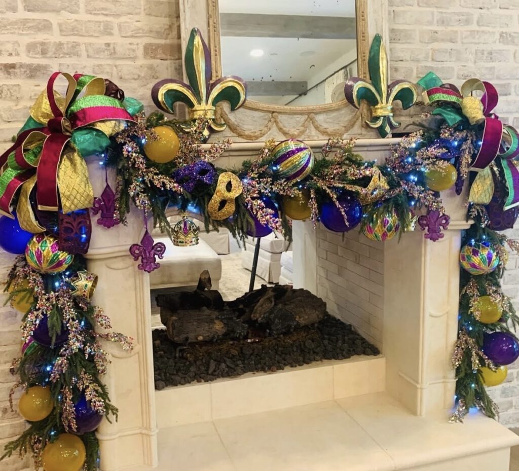 White fireplace with mardi gras garland featuring large bows, beads and large fleur de lis decor