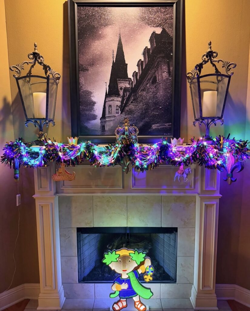 Mardi Gras mantel with colorful light-up garland in purple, green, and gold, topped with crown accents and bright string lights, with lantern decor on both sides of the fireplace.