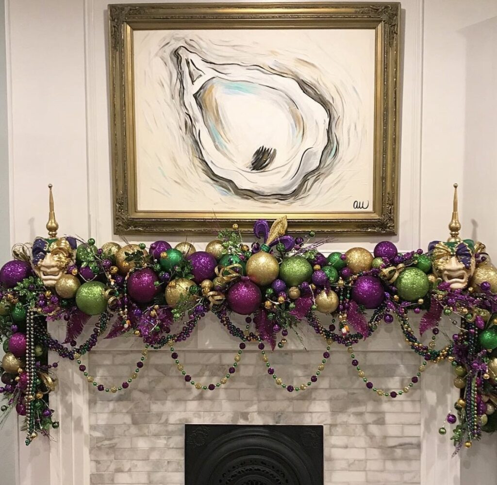 Marble fireplace with a full Mardi Gras ball garland in purple, green, and gold, bead swags, and masks at both ends beneath framed artwork.