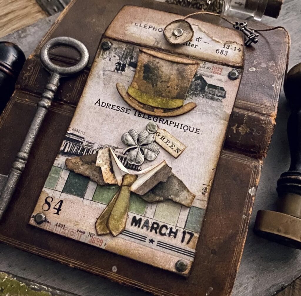 Vintage St. Patrick’s Day tag or journal card with a top hat, tie embellishment, small shamrock, and “March 17” text.