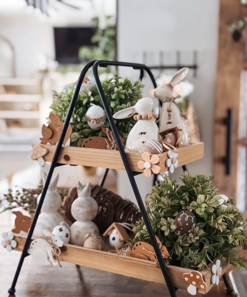 Neutral Easter two-tier tray stand with white bunny figurines, faux greenery, speckled eggs, wood beads, and wooden flower accents.