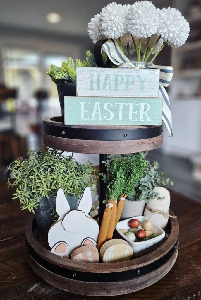 Round wooden two tier tray with wooden bunny and sign with white flowers and greenery