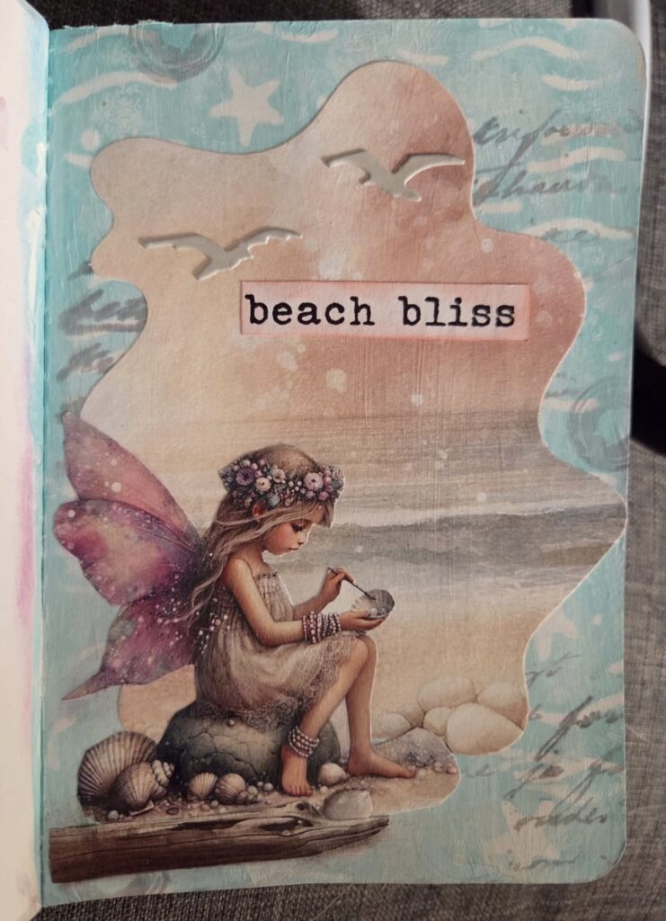 Beach scrapbook journal page with pastel ocean background and “beach bliss” title, featuring a fairy girl sitting on rocks with seashells.
