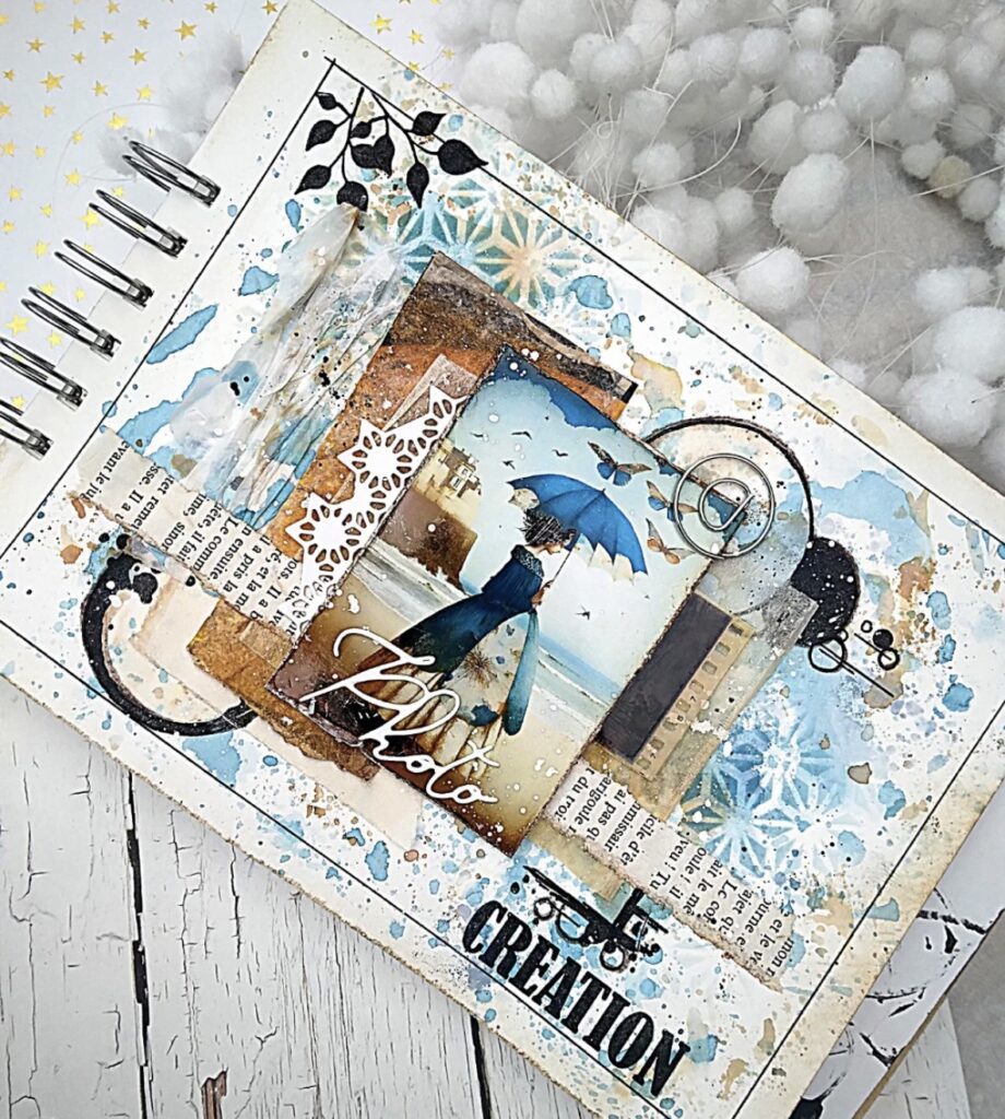 Mixed media beach art journal page with blue paint splatter texture, layered collage pieces, and a beach photo with the word “creation.”