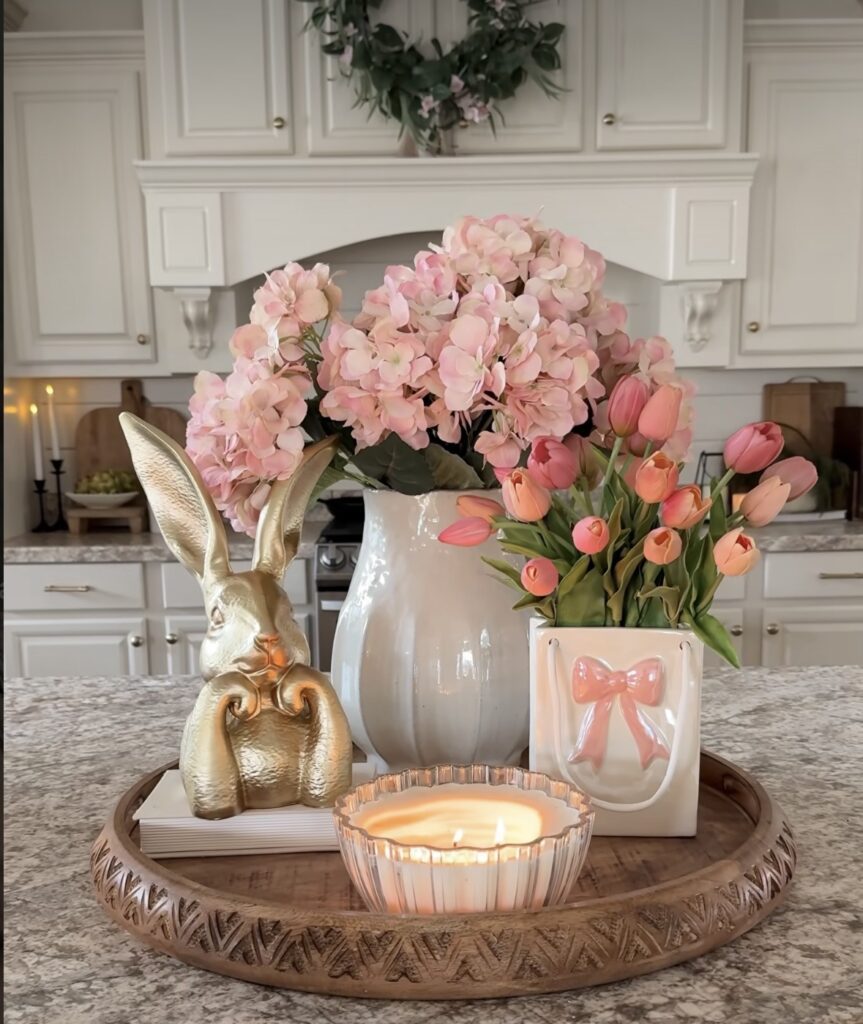 Easter tray decor with gold bunny statue, pink hydrangeas, coral tulips, and soft pastel spring florals arranged on a round wooden tray.