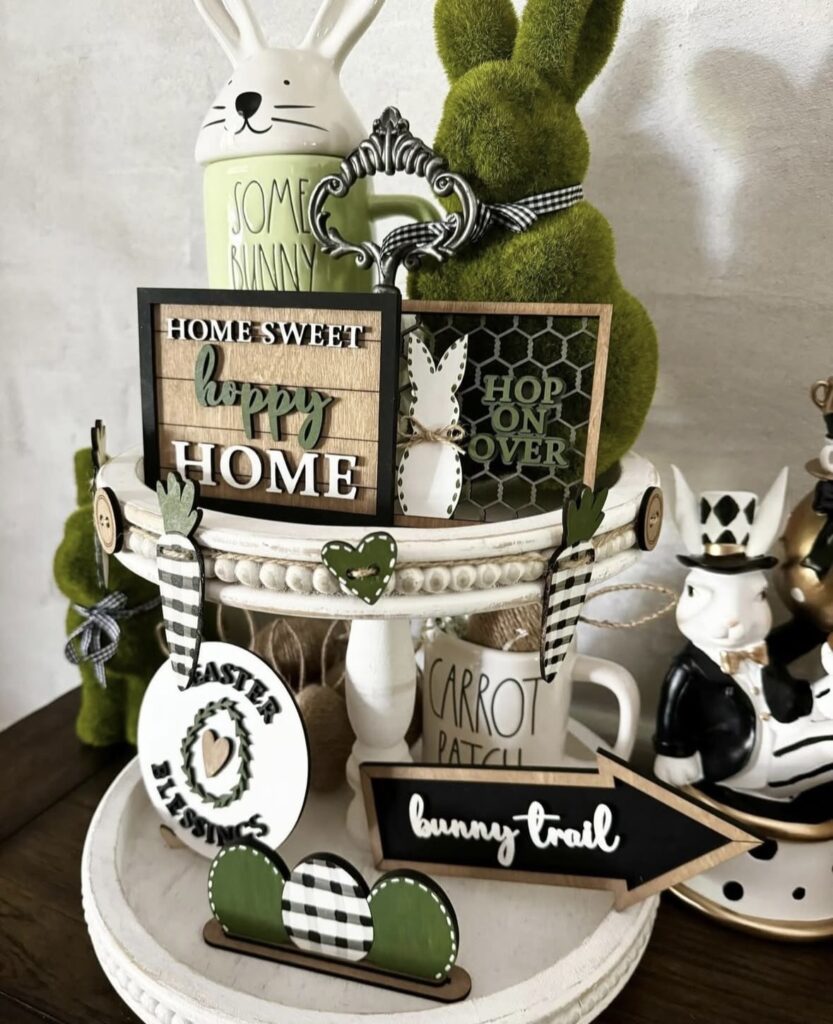 Easter tiered tray decorated with bunny signs, greenery, carrot themed decor, and black and white farmhouse accents.