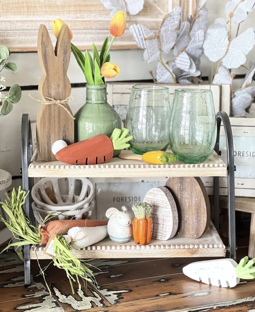Spring rectangle tiered tray styling with wooden bunny silhouette, green bottle with tulips, faux carrots, Easter egg shapes, and a small bunny figurine.