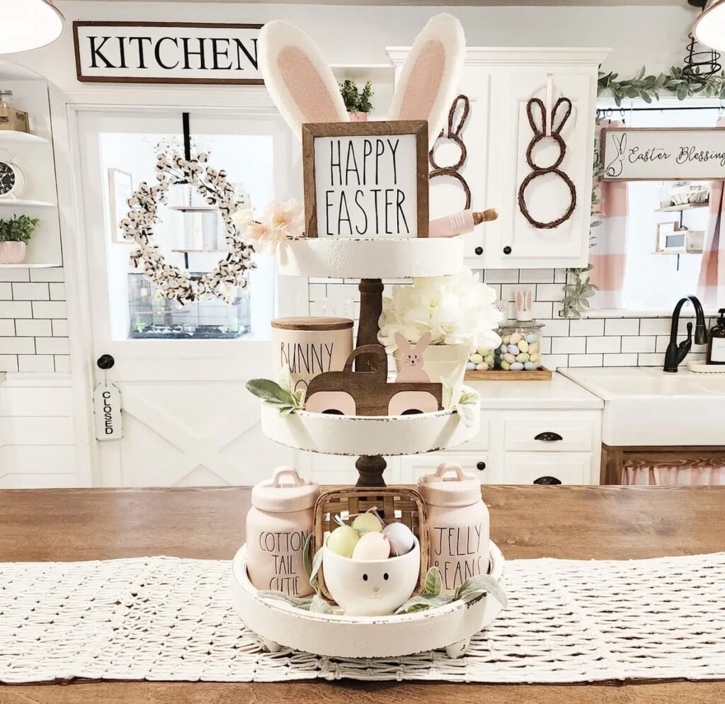 Easter tiered tray centerpiece on dining table with bunny figurines, potted florals, pastel decor, and farmhouse spring styling.