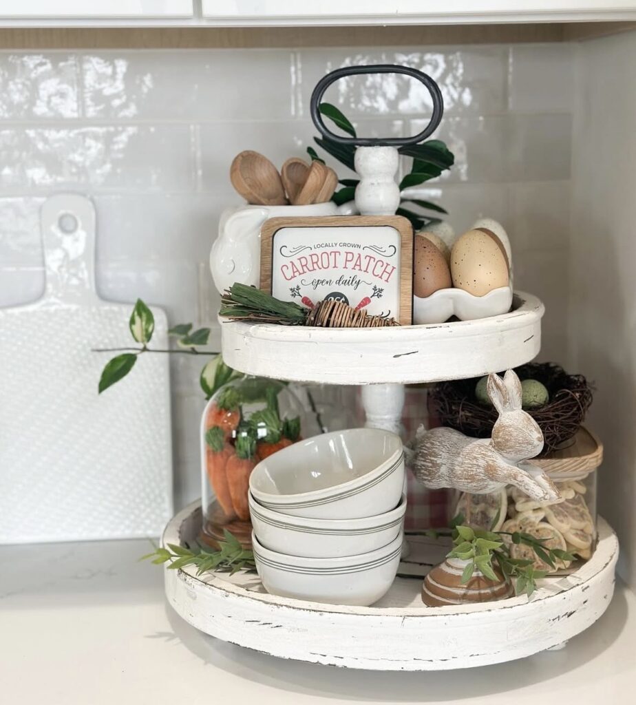 White Easter tiered tray with “Carrot Patch” sign, stacked bowls, bunny figurine, jar of carrots, and greenery accents.