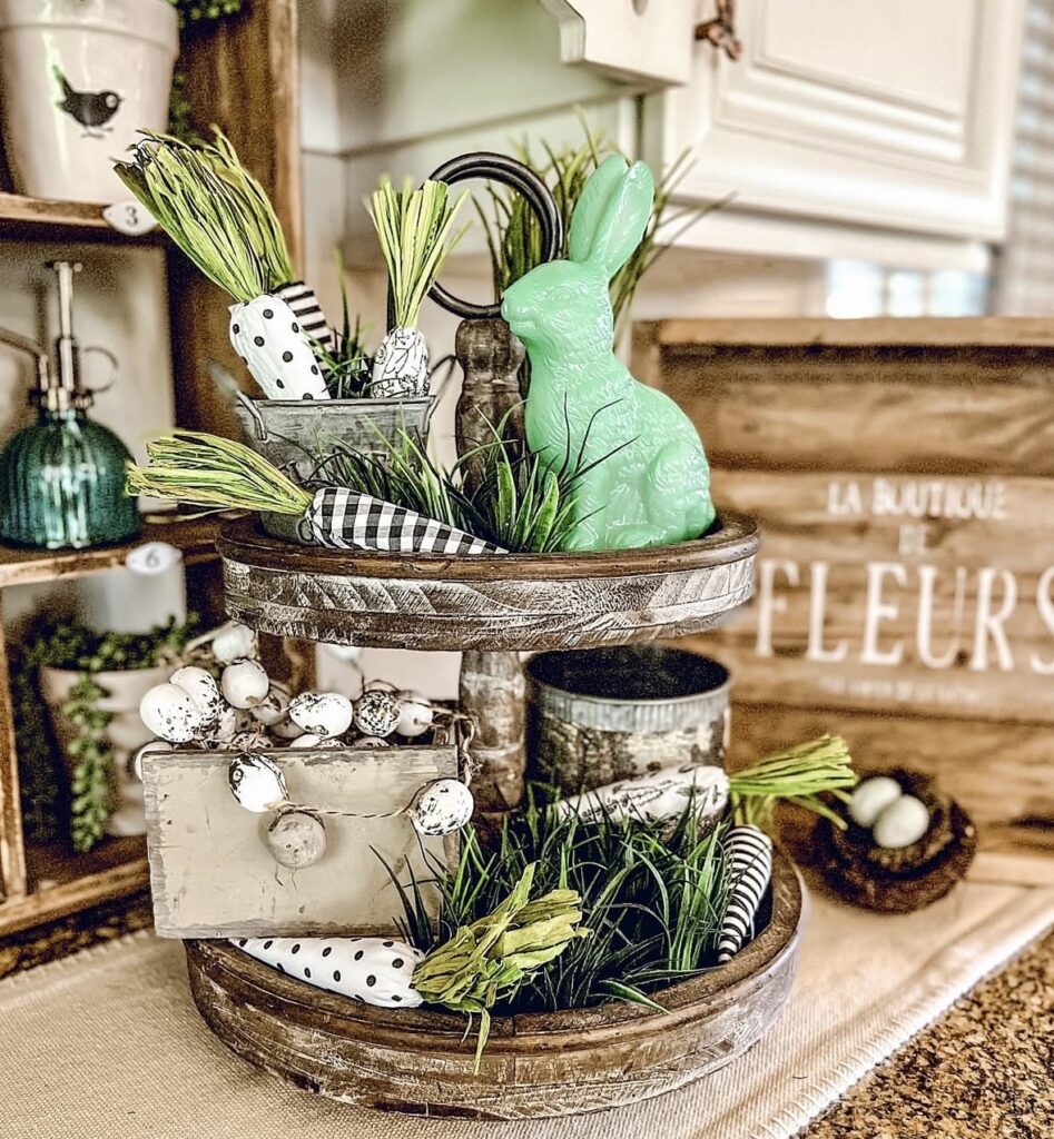 Rustic farmhouse Easter tiered tray with a green bunny, faux carrots, speckled egg garland, and black and white spring decor.