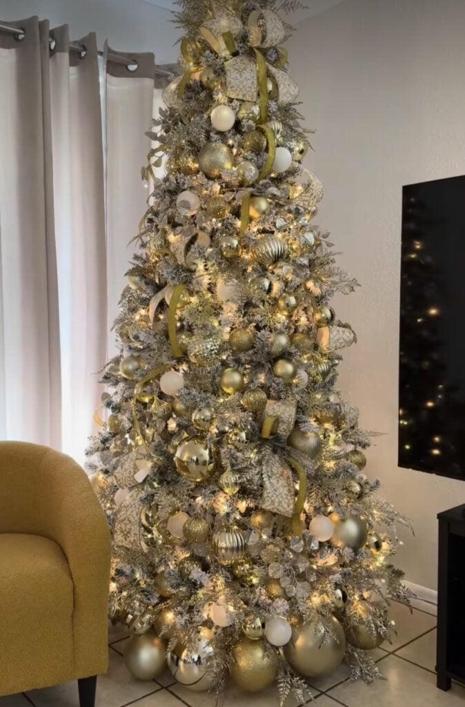 Gold Christmas tree decorated with metallic ornaments, bows, and warm white lights.
