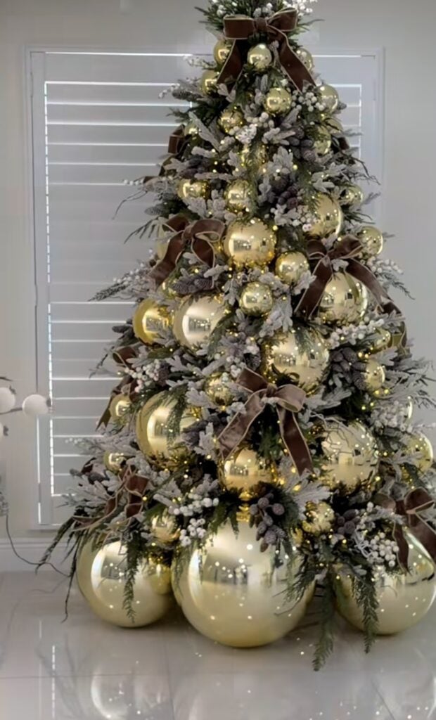 Luxury gold Christmas tree with oversized ribbon and designer holiday decorations.