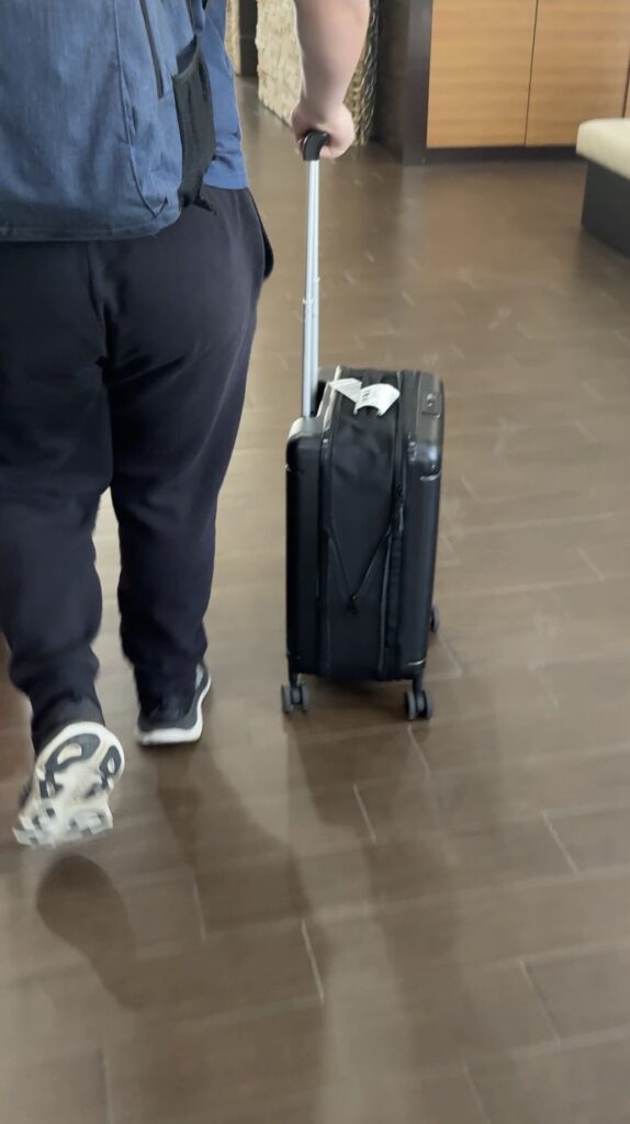 Avio collapsible carry on luggage being rolled through a hotel lobby on spinner wheels