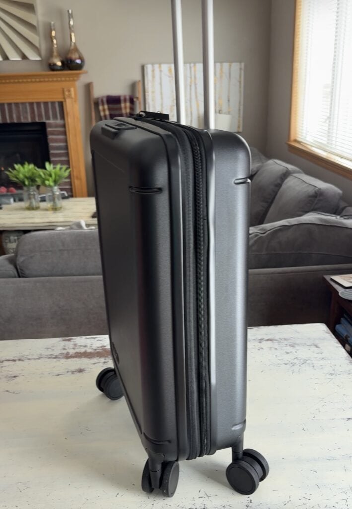 Side view of Avio foldable carry on luggage showing the collapsible compression zipper detail in black hardshell