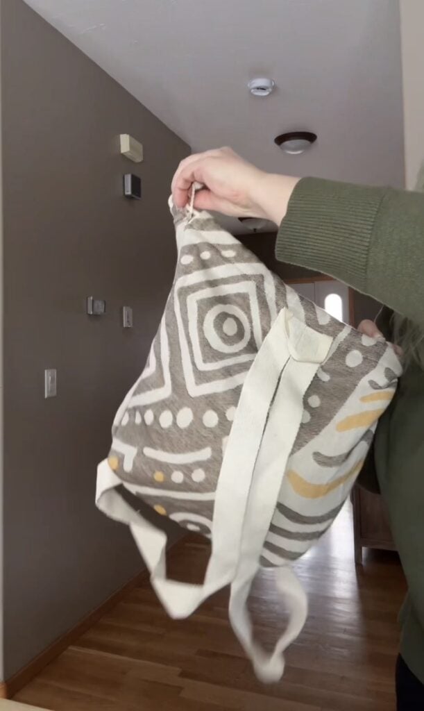 Sand Cloud towel backpack being held up to show the backpack straps and mudcloth geometric design on the outside