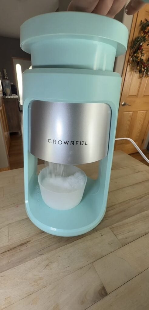 Crownful snow cone machine actively shaving ice into the included cup underneath.