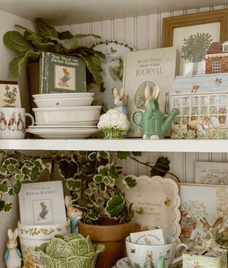 Beatrix Potter Easter kitchen shelf decor with Peter Rabbit books, bunny figurines, cabbage dishware, a green watering can, and layered vintage-style spring accents.