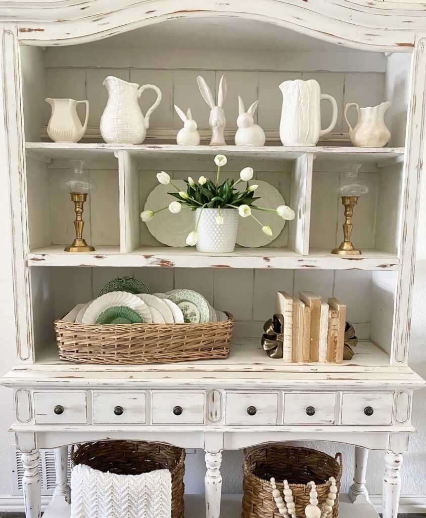 Minimal Easter hutch decor with white pitchers, brass candlesticks, white tulips, woven basket, green plates, and simple neutral spring styling.