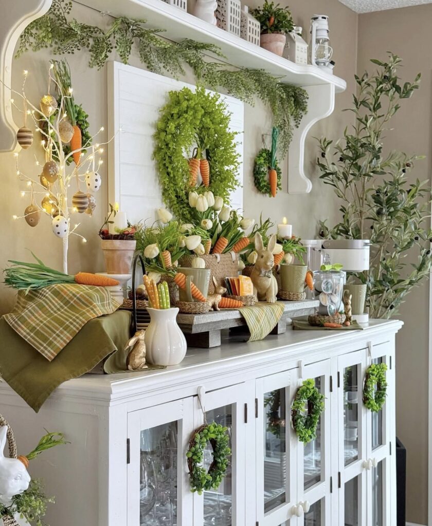 Charming Easter hutch decor with carrot accents, tulips, bunny figurines, egg ornaments, greenery wreaths, and layered spring cottage styling.