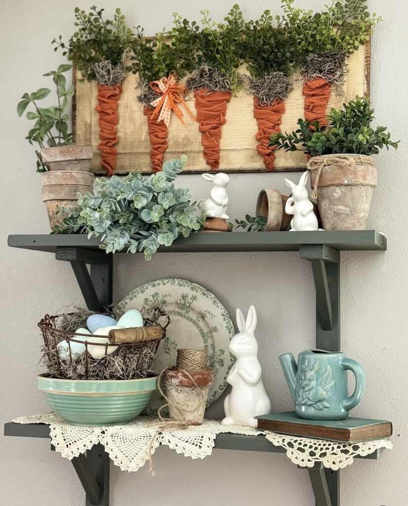 Rustic Easter shelf decor with fabric carrots, pastel eggs, white bunny figurines, greenery, and vintage-inspired spring accents.