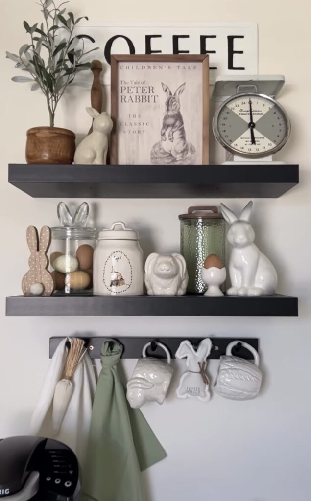Simple Easter kitchen shelf decor with Peter Rabbit art, bunny mugs, ceramic rabbits, glass jars of eggs, and soft green and white accents.